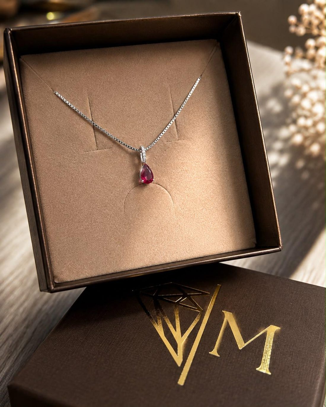 Pendentif en or blanc avec pierre rouge taille poire et diamants, présenté dans un écrin MAVELIA